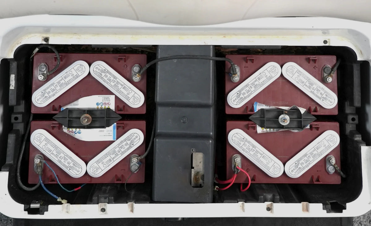 Old lead-acid golf cart batteries installed in the battery compartment before lithium replacement