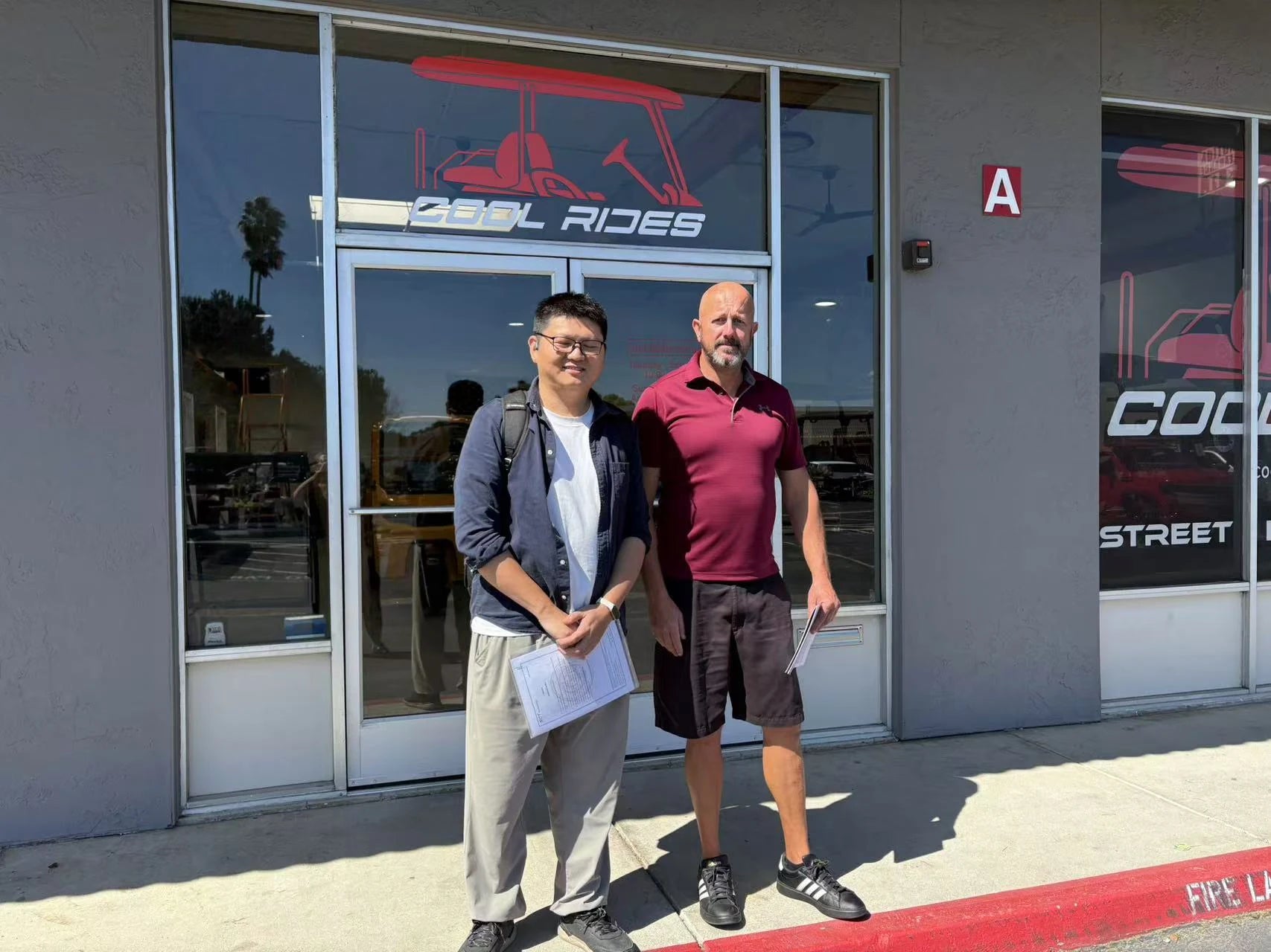 Two people photographed outside a golf cart business