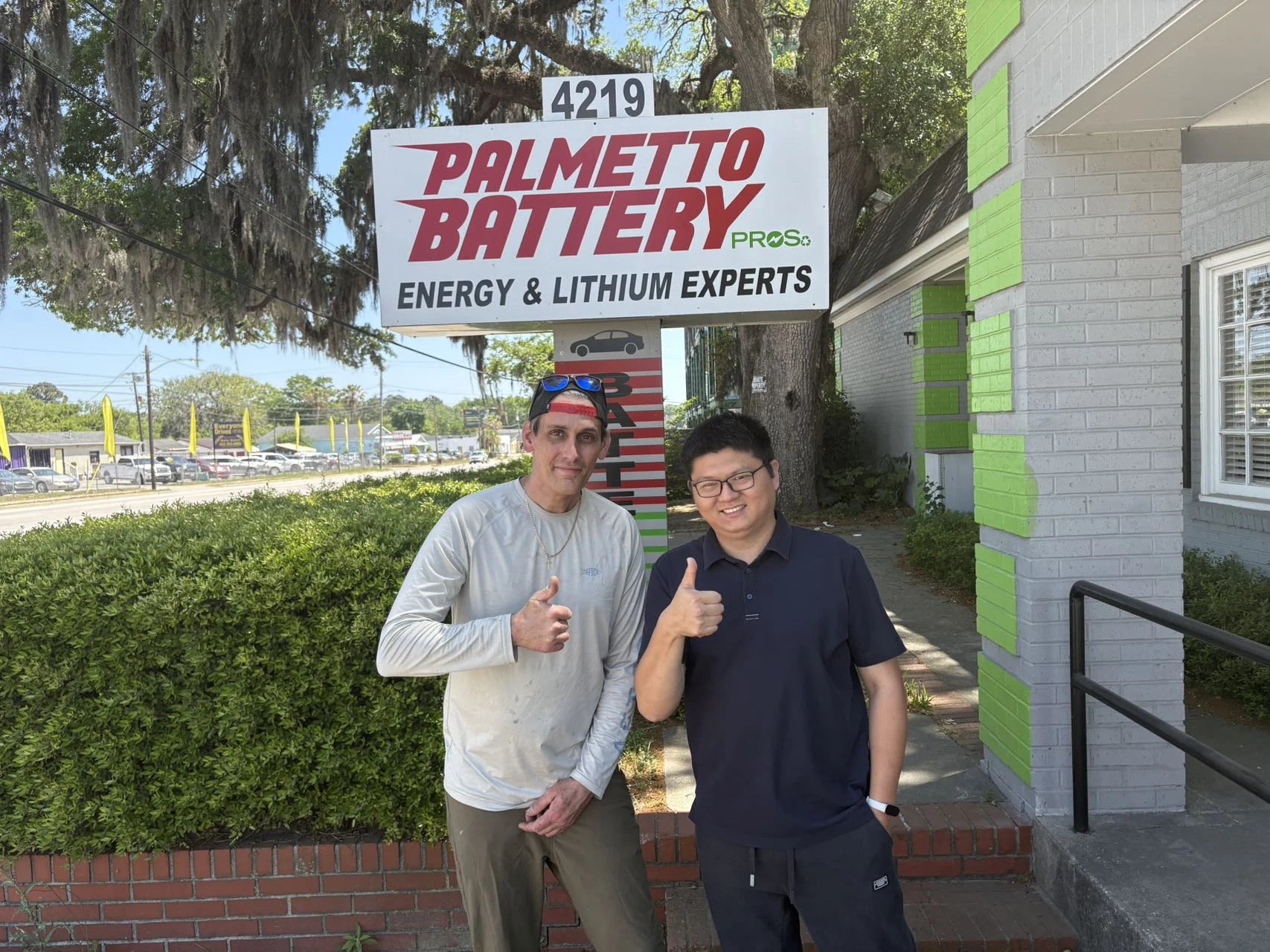 Two people photographed outside a battery and golf cart business