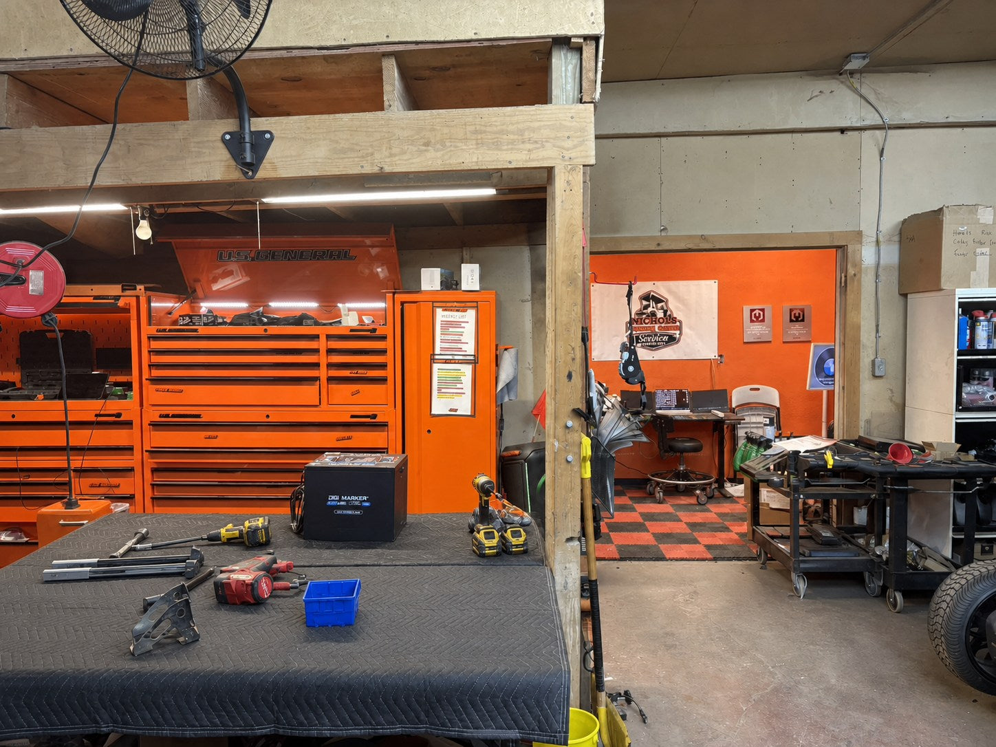 Golf cart service bay with an organized workbench, DigiMarker battery, orange tool storage, and service equipment